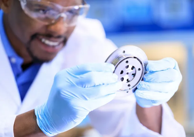 A man in a lab coat is holding a metal object