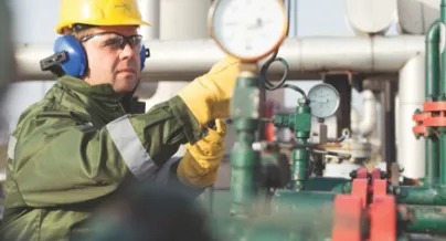 A man in a safety helmet and safety glasses is working on a gas pipeline