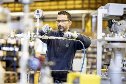 John Crane technician in a workshop assembling and inspecting industrial piping equipment.