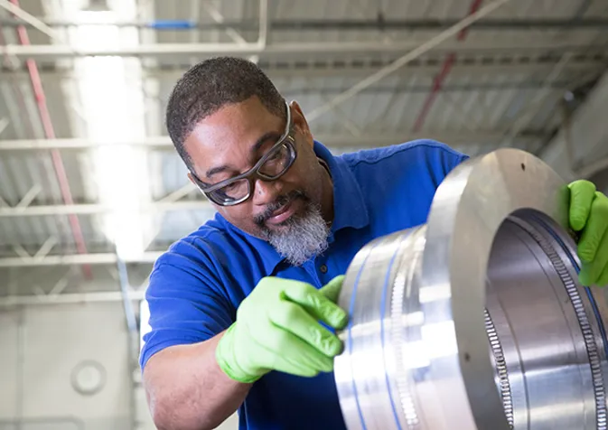 A man in a blue shirt is working on a large metal object