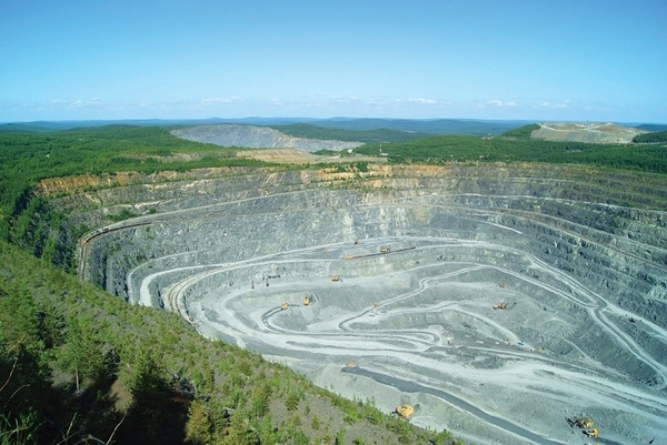 Open-pit quarry with terraced levels surrounded by greenery