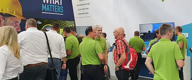 A group of people standing around a large screen