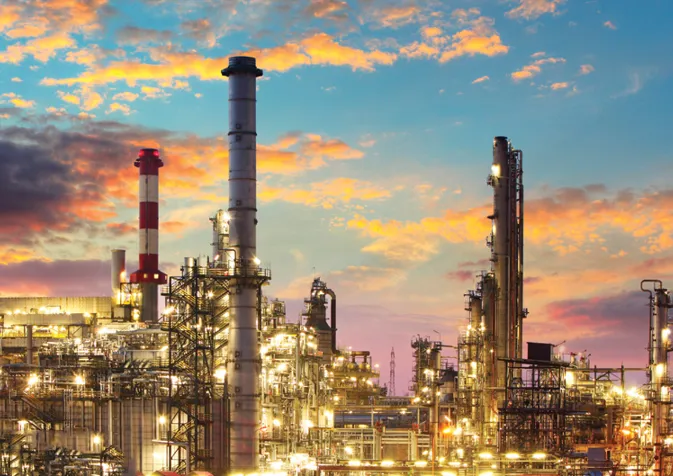A refinery at sunset with a cloudy sky
