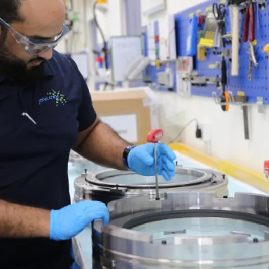 A man in blue shirt and gloves working on a machine