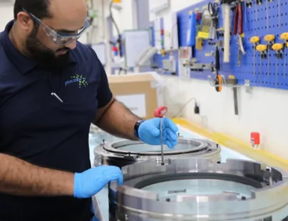 A man in blue shirt and gloves working on a machine
