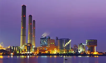 A large industrial plant with smoke stacks at dusk