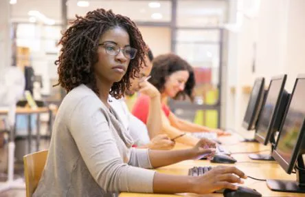 A woman is sitting at a computer in a library