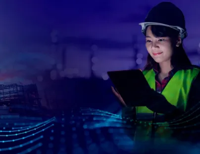 A woman in a hard hat and safety vest holding a tablet