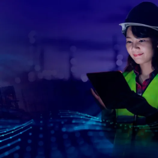 A woman in a hard hat and safety vest holding a tablet computer