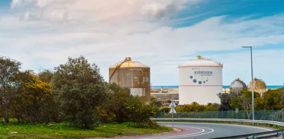 Industrial hydrogen storage tanks near a curved road and greenery.