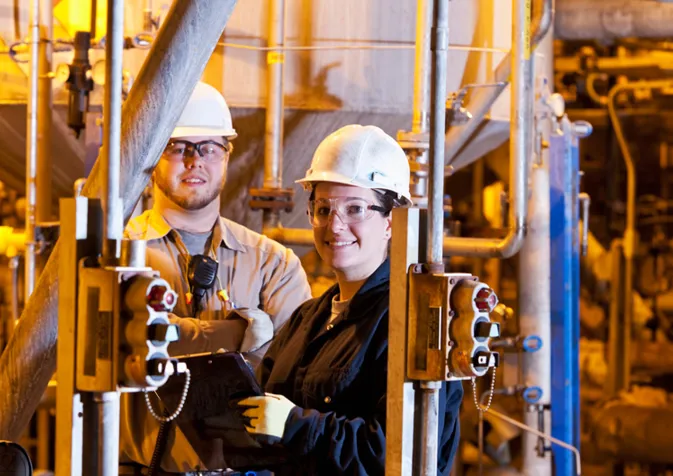 Two people in hard hats standing in front of a large industrial machine