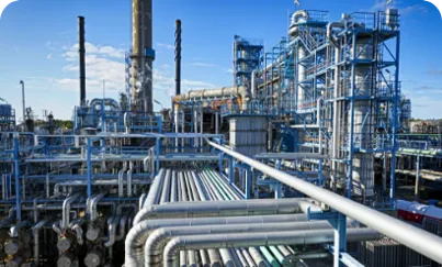 An industrial facility with an intricate network of pipes set against a bright blue sky