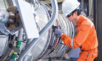 A man in an orange uniform working on a large pipe