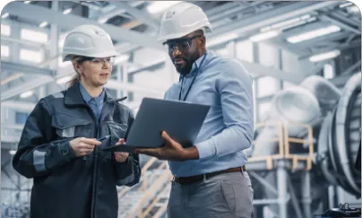 Two people in hard hats and hard hats looking at a laptop