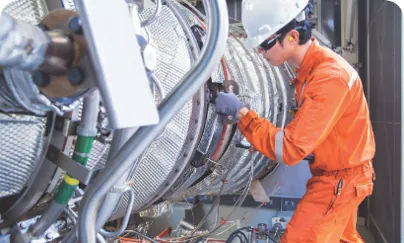 A man in an orange uniform working on a large machine