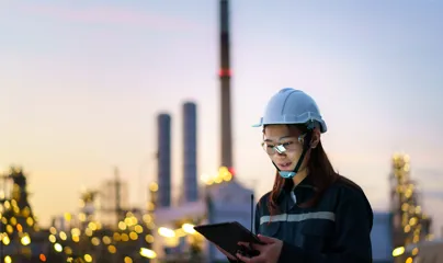 A woman in a hard hat and helmet holding a tablet