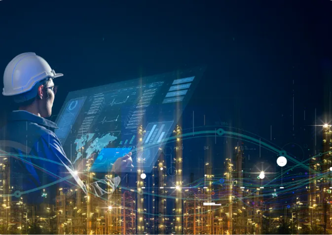 A modern manufacturing facility at night with an overlaid image of a person working on a laptop